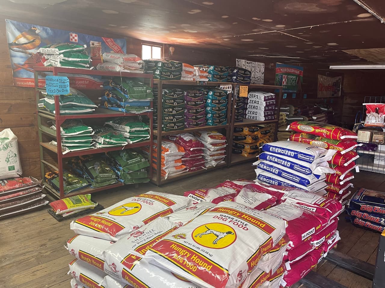 Wild bird feed, VICTOR and Hi-Point dog food, and goat mineral stocked side by side on the sales floor at Mustang Creek Feed Seed & Supply in Rio Vista, Texas